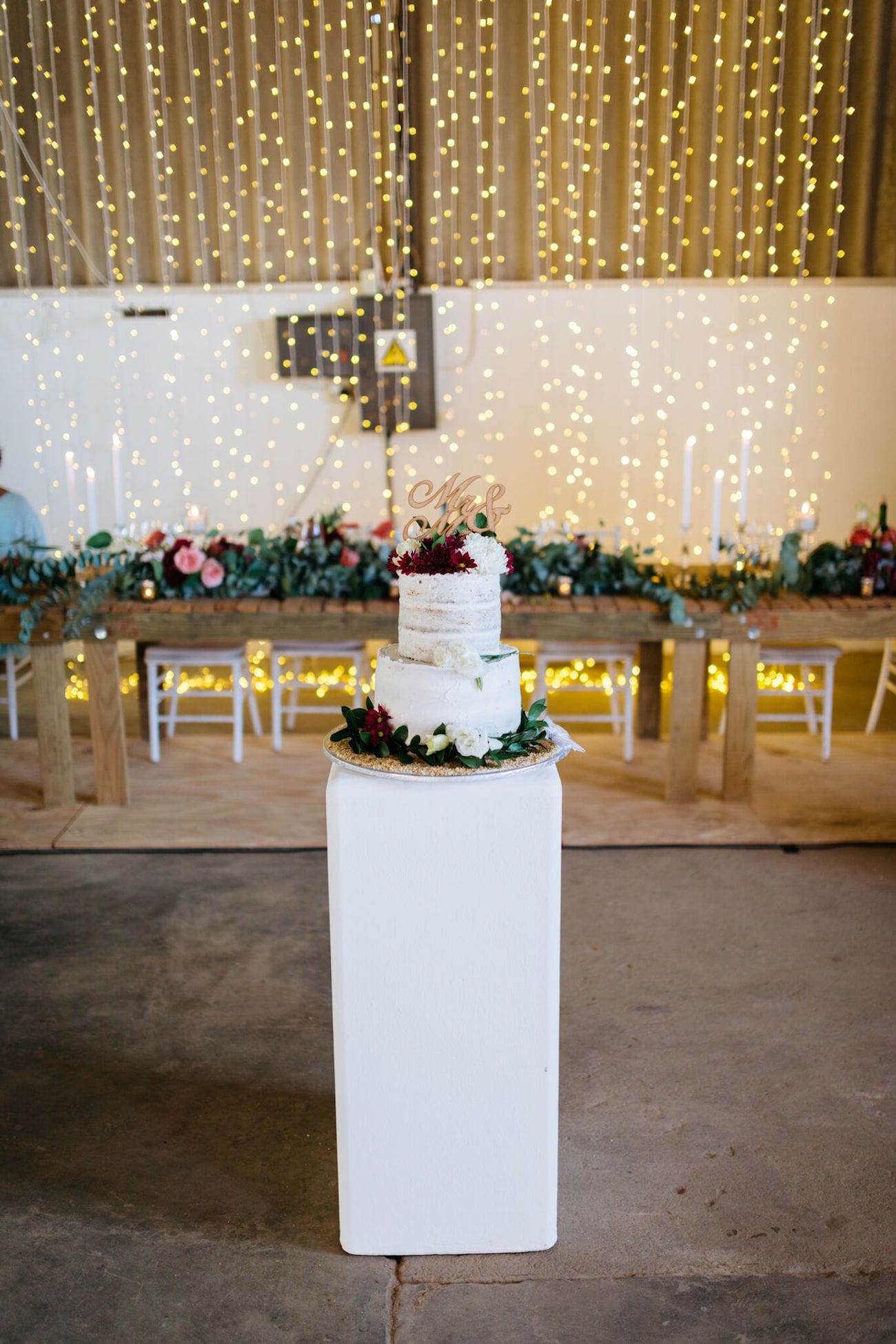 Semi-naked wedding cake with twinkle light backdrop | Credit: Matthew Carr